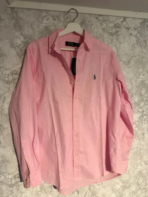 Rosa linneskjorta Ralph Lauren - Tjena, säljer nu en mycket fin rosa linneskjorta från Ralph Lauren, den är oanvänd och har inga defekter. Storlek S men passar även M, har du någon fundering är de bara att skriva och ge gärna prisförslag!!