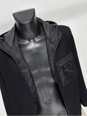 Svart Prada nylon jacka  - Elegant och snygg jacka från Prada i storlek M. Jackan är princip ny då den använts varsamt ett fåtal gånger. Väldigt unik modell som inte synts allt för ofta. Köpt för ca 15000kr i Barcelona för två år sedan. Hör av er vid intresse eller vid önskan om fler bilder!