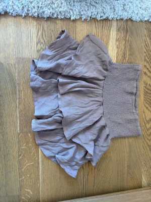 Beige volangkjol från SHEIN - Supersöt beige kortkjol från SHEIN med bred smock i midjan och flera lager volanger. Kjolen har en luftig och flowy känsla, perfekt för varma dagar. Tillverkad i ett lätt syntetmaterial som ger en skön passform.