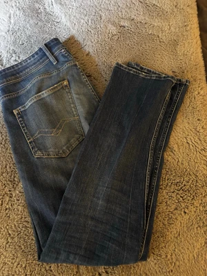 Blå jeans från Replay - Snygga blå jeans från Replay med klassisk femficksdesign och dekorativa sömmar på bakfickan. Jeansen har en rak passform och är gjorda i slitstarkt denimtyg. Perfekta för en avslappnad och trendig stil.