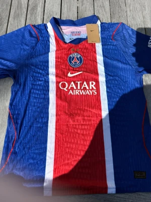 O. Dembélé #10 – Hemma PSG (storlek M) - O. Dembélé #10-tryck. Nya säsongens hemmatröja. Storlek M. Helt ny och aldrig använd. Skickas snabbt 🚚💨  Mått (M): Halvt bröstmått 51 cm • Längd 72,5 cm • Ärmbredd 22,5 cm • Axelbredd 43 cm • Ärmlängd 39 cm • Manschett 18 cm.  🔥 Player Edition – tajtare passform än vanliga supportertröjor.  📩 Skicka gärna ett meddelande vid frågor eller prisförslag! 🛍 Bundle-rabatt upp till 20%! 📦 Skickas samma eller nästa dag.