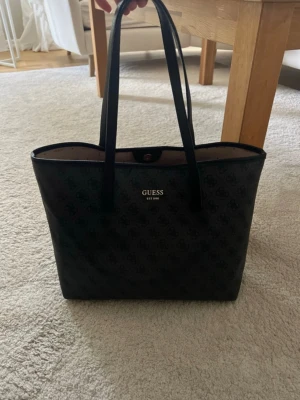 Handväska från GUESS - Säljer min handväska från Guess. Super fin och tagits väl hand om. Utåt sett är väskan i väldigt bra skick, insidan har lite lösa trådar men inget som påverkar väskans funktion. 