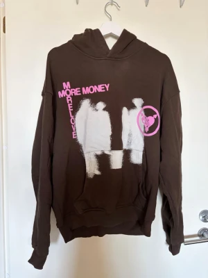 Brun hoodie More Money m - Säljer en brun hoodie med stor huva och coolt tryck i vitt och rosa framtill. Texten 'MORE MONEY MORE LOVE'. 