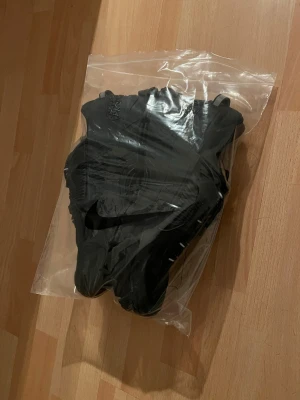 Svarta Nike sneakers  - Säljer ett par helsvarta Nike sneakers med låg profil och klassisk snörning. Skorna har en sportig design med diskret Nike-logga på sidan och tåliga material. Perfekta för dig som gillar stilrena och funktionella sneakers.