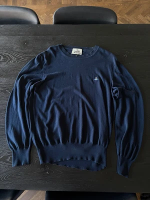 Mörkblå stickad tröja Vivienne Westwood - Mörkblå stickad tröja från Vivienne Westwood med rund halsringning och ikonisk broderad logga på bröstet. 