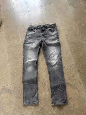 Guess Jeans - Snygga grå jeans från Guess i slim fit-modell med slitna detaljer och tvättade partier framtill. Fint skick!