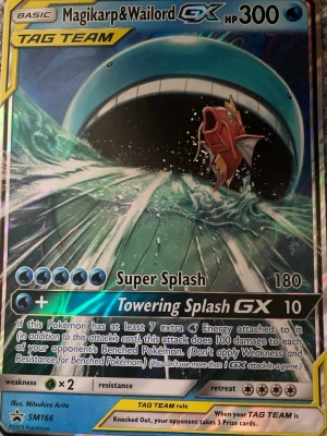 Pokémonkort Magikarp & Wailord GX - Säljer ett Pokémonkort med Magikarp & Wailord GX från TAG TEAM-serien. Kortet har en färgstark och glansig design med blå och röda toner. Det är illustrerat av Mitsuhiro Arita och har attackerna Super Splash och Towering Splash GX.