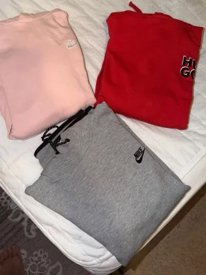 Grå Nike hoodie med svart logga - Säljer en stilren grå hoodie från Nike med svart logga på bröstet. Hoodien har svarta detaljer vid ärmslut och nederkant samt en dragkedjeficka på ena ärmen. Perfekt för dig som gillar sportig och enkel stil.