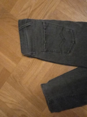 Svarta Replay jeans med raka ben - Snygga svarta jeans från Replay med klassisk femficksdesign och raka ben. Jeansen har diskreta slitningar och logga på fickan. Perfekta för dig som gillar en stilren look och vill ha ett par jeans som funkar till det mesta.