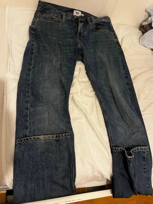 Mörkblå raka jeans med uppvik - Säljer ett par mörkblå jeans med raka ben och stora uppvik nertill. Jeansen har klassisk femficksdesign och orangea sömmar. Materialet är denim i bomull och passformen är avslappnad. Perfekta för en chill och avslappnad stil. W31L34
