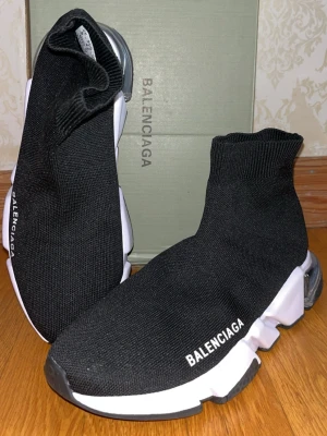 BaIencIaga skor  - Svarta Balenciaga Speed Trainer sneakers med stickad ovandel i textil och vit chunky sula. Strumpliknande passform och logga på sidan. Snygg, futuristisk design med svart och vit färgkombo. Perfekta för dig som gillar streetwear och vill sticka ut.