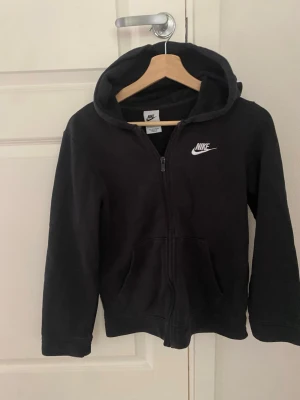 Svart zip hoodie från Nike - Klassisk svart hoodie från Nike med dragkedja framtill, storlek 147-158 cm 