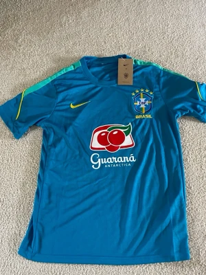 Blå Brasilien Nike fotbollskit - Säljer ett blått Brasilien fotbollskit från Nike, bestående av tröja och shorts. Setet har gula detaljer, CBF-logga och Guaraná Antarctica-tryck på tröjan. Tillverkat i lätt och ventilerande material, perfekt för träning eller match.