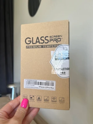 Skärmskydd i glas till iPhone 13 Pro Max - Tempererat skärmskydd till iPhone 13 Pro Max. Genomskinligt och tillverkat i tåligt (härdat) glas. Förpackningen innehåller: Rengöringsduk, Guide stickers, Dust absorbers, Dry wipes och Wet wipes. 