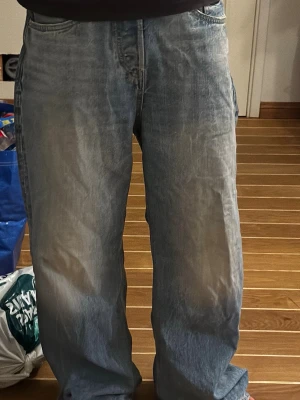Ljusblå straight loose fit jeans H&M - Säljer ett par ljusblå jeans från H&M i straight loose fit-modell. Jeansen har klassisk femficksdesign, raka ben och avslappnad passform. Tillverkade i denim med snygg tvättad look och subtila slitningar. Perfekta för en chill och trendig stil. Kostar 450kr nya