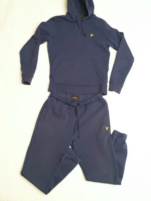 Mörkblått loungewear-set med hoodie - Mörkblått loungewear-set från Lyle & Scott med matchande hoodie och byxor. Hoodien har dragsko och känguruficka.