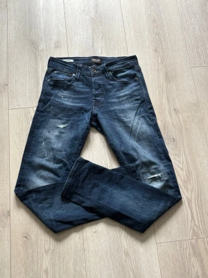 Jack & Jones jeans med slitningar - Mörkblå Jack & Jones jeans med slitningar, modell slim/glenn storlek w29 L 32. Hör av er vid funderingar