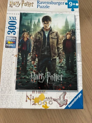 Harry Potter pussel 300 bitar - Harry Potter pussel från Ravensburger med 300 XXL-bitar. Motivet är från Deathly Hallows Part 2 och visar Harry, Hermione och Ron framför Hogwarts. För åldrar 9+ och levereras i en vit och blå kartong med tydlig Harry Potter-design. Pusslats 1 gång 
