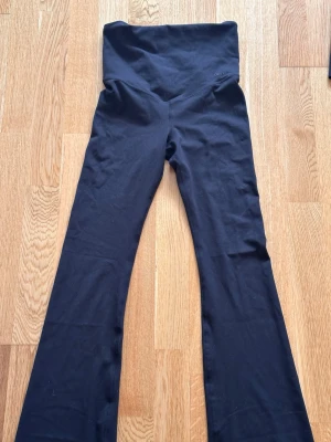 Svarta gravid bootcut leggings med hög midja - Säljer ett par svarta gravid leggings från aimin med hög midja och utsvängda ben. De är stretchiga och bekväma, perfekta för en trendig och avslappnad look. Materialet är mjukt och följsamt, vilket gör dem sköna att bära hela dagen.