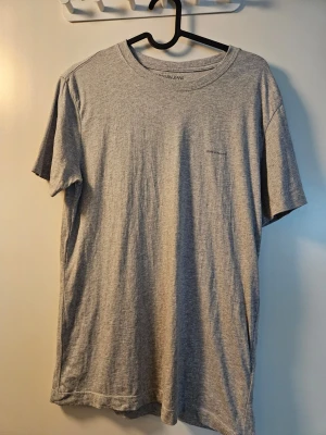 Calvin Klein Jeans grå t-shirt - Grå t-shirt från Calvin Klein Jeans. T-shirten har texten "CALVIN KLEIN JEANS" tryckt på bröstet. Den har korta ärmar och en rund halsringning. Passformen är slim fit.  Endast använd någon enstaka gång.   Nytvättad med parfymfritt tvättmedel.  Observera att en liten del av texten ramlat av, se bild.