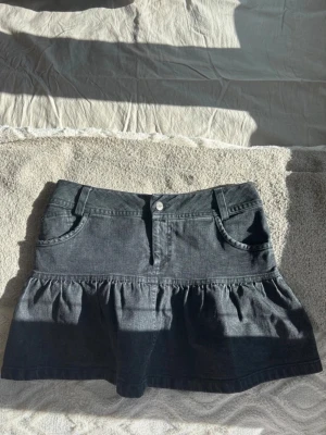 Svart volangkjol i denim - Kort svart jeanskjol med volangkant! Köpt på vinted, säljer då den tyvärr inte passade. I fint skick!