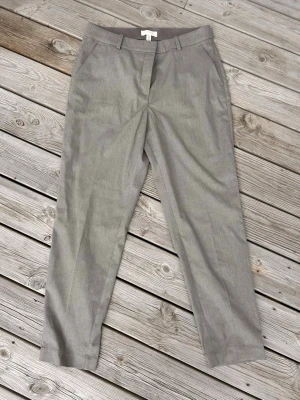 Beige slaks med rak passform - Klassisk beige slaks med rak passform och minimalistisk design. Tillverkad i ett mjukt tyg som ger en clean och stilren look. Perfekt för dig som gillar enkelhet och tidlös stil. Resår i ryggen.