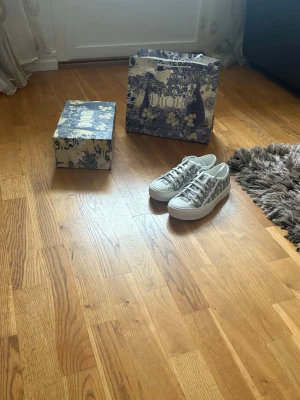 Dior gråvita låga sneakers - SKICKA GÄRNA PRISFÖRSLAG ❤️Säljer ett par superfina WALK’N’DIOR Platform Sneakers i storlek 38. Modellen har Diors klassiska "Oblique Embroidered Cotton"-mönster i grå/vitt. Skorna är 100% äkta och köpta digitalt via Farfetch (nypris 11 500 kr). Digitalt ordererkännande/kvitto finns och bild på detta kan visas vid intresse samt skickas med vid köp.💕💕