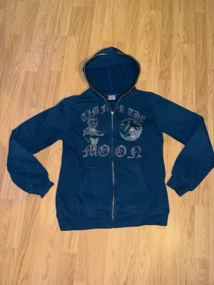 Blå hoodie med strass och tryck - Säljer en blå Aim for the moon zip-hoodie med huva och fickor framtill. Storlek L men passar även M. Hör av dig vid funderingar!