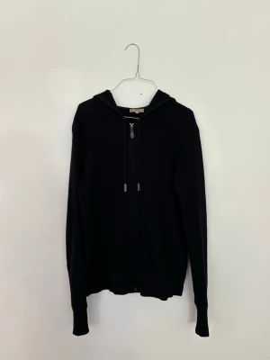 Burberry zip hoodie, strl M - Svart Burberry zip hoodie i storlek M Herr. Stilren modell med dragkedja och Burberry-detaljer. Bra begagnat skick med normalt slitage. Ett mindre hål finns framtill bredvid dragkedjan längst ner (se bild), vilket är inräknat i priset. Skickas eller hämtas enligt överenskommelse. Pris: 2 200 kr eller bud.