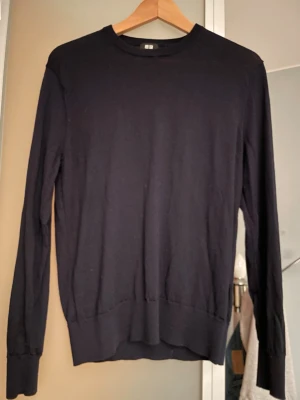 Mörkblå merinoull tröja  - Mörkblå stickad merinoull tröja från Uniqlo i storlek S. Den är i mycket gott skick och har bara används ett fåtal gånger. Tröjan har en enkel, klassisk design som passar perfekt till olika outfits. Den sitter bra och är i mjukt och skönt material. 