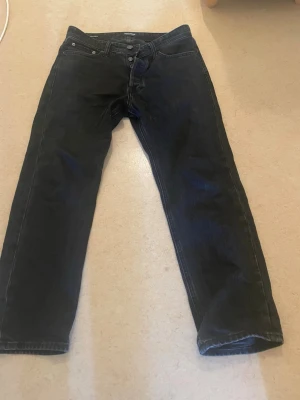 Svarta relaxed jeans från Jack & Jones - Säljer ett par svarta relaxed fit jeans från Jack & Jones, modell Chris. Jeansen har klassisk femficksdesign, raka ben och knappgylf. Tillverkade i slitstarkt denimtyg som ger en avslappnad och trendig look.