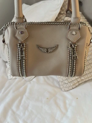 Beige handväska med kedjedetaljer - Snygg Zadig Voltaire likande handväska i beige, finns små fläckar som inte syns mycket alls💕