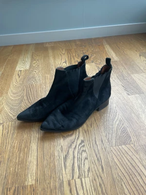 Svarta boots  - Säljer ett par svarta boots med spetsig tå och låg klack. Skorna har resår på sidorna och dragflikar både fram och bak för enkel påtagning. Klassisk och stilren modell som passar till många olika outfits.