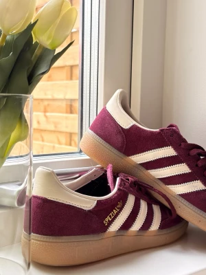 Adidas Handball Spezial vinröda sneakers - Säljer mina vinröda Adidas Handball Spezial sneakers i mocka material. Perfekta för dig som gillar retrostil och streetwear.                                                                                                ⭐️Säljes i nyskick, utan defekter & slitage, never used                                                                           ️⭐️Storlek38                                                                            💭Har du frågor? Skriv på annonsen och jag svarar så fort jag kan