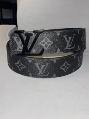 Svart  monogram bälte - Snyggt svart skärp från  med klassiskt monogrammönster och stor  i metall som spänne. Skärpet har en stilren design och är tillverkat i skinn med detaljer i svart. Perfekt accessoar för att lyfta din outfit.