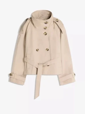 Kort beige trenchcoat med bälte - Stilren kort trenchcoat i beige med dubbelknäppning, axelklaffar och bälte i midjan. Jackan har klassiska detaljer som knappar vid ärmslut och två fickor framtill. Perfekt för en trendig och tidlös look.
