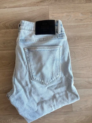 Ljusblå raka jeans från NEUW  - Säljer ett par ljusblå jeans med klassisk femficksmodell och raka ben. Jeansen har en svart patch bak i midjan och är tillverkade i ett mjukt denimtyg. Perfekta för en avslappnad och trendig look. Modellen är Iggy skinny. 