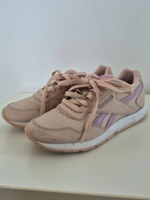 Reebok Royal Glide sneakers - rosa - Jättefina och bekväma sneakers från Reebok i en fin puderrosa färg med lila detaljer.  Modell: Royal Glide (CN7201). Sparsamt använda och i gott skick, sulan har mycket kvar att ge.  OBS angående storlek: De är märkta som storlek 38, men upplevs som mindre och trånga i passformen. Jag har kontrollmätt innermåttet till ca 24 cm. De passar därför bäst för dig som vanligtvis har storlek 37.