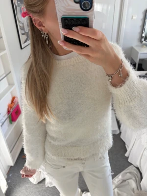 Vit fluffig stickad tröja - Mysig vit stickad tröja med fluffig textur och rund hals. Tröjan har spetskant ned till, super fin💗 skriv vid frågor