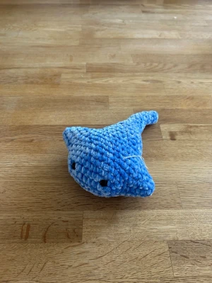 Blå virkad stingrocka - Söt handvirkad stingrocka i blått och vitt garn med svarta säkerhetsögon. Mjuk och gosig, perfekt som dekoration eller leksak. Unik och charmig design som passar både som present eller till dig själv.