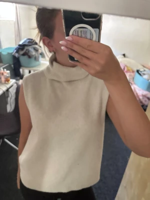 Vit stickad linne liknade med polokrage - Säljer en vitt stickat linne liknande tröja med hög polokrage. Tröjan är ärmlös och har en rak, något loose passform. Perfekt att styla över en skjorta eller långärmad tröja för en trendig lager-på-lager-look. Står att den är i XL, men jag har XS/S o den passar jättebra på mig!