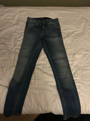 Blå raka jeans från tiger of sweden - Säljer ett par klassiska blå jeans med raka ben och lätta fade detaljer. Jeansen har fem fickor och normal midja. Perfekta till en avslappnad stil och passar till det mesta. Materialet är denim i bomull.