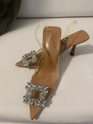 Transparenta pumps med strassdetalj - Säljer ett par eleganta pumps med transparent plast och spetsig tå. 