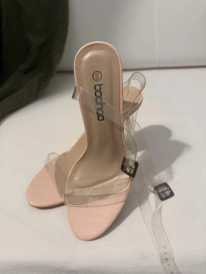 Nude pumps med transparenta remmar - Snygga pumps från Boohoo i nude färg med transparenta plastremmar och fyrkantig tå. 