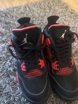 Svarta och röda Air Jordan sneakers - Säljer ett par snygga Air Jordan sneakers i svart mocka med röda detaljer och meshpaneler. Skorna har klassisk Jumpman-logga på plösen och cool design med högt skaft. Perfekta för dig som vill sticka ut med din stil. Köptes via vinted, tyckte det var tajt på mig. Storlek 38 