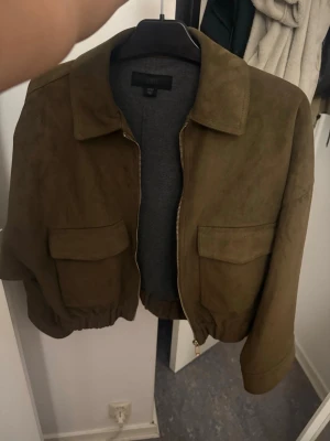 Olivgrön kort jacka med fickor från zara - Mocka jacka i grön från zara som jah aldrig använt då de inte min stil längre så den är fortfarande helt ny