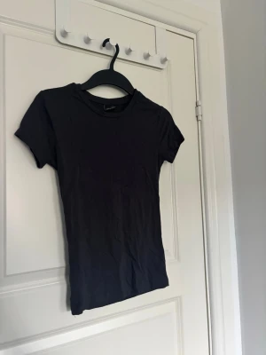 Svart t-shirt från Gina Tricot - En enkel svart t-shirt från Gina Tricot i storlek XS. T-shirten har korta ärmar och rund halsringning.