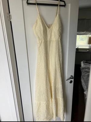 Lång ljusgul spetsklänning med smala band - Söt långklänning i gul spets med smala axelband och v-ringning. Klänningen har broderade detaljer och en luftig passform. Inbyggd BH/ ilägg i bysten.  Köpt i Grekland innan sommaren.