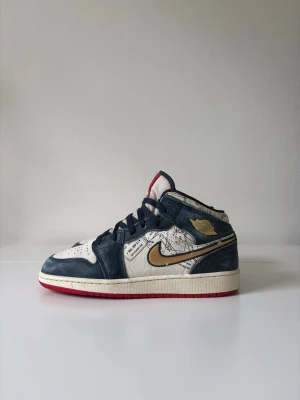 Nike Air Jordan 1 Mid SE ”Take Flight” (FN1353-400) - Stl 40 - Säljer ett par unika Air Jordan 1 Mid SE GS ”Take Flight” i storlek 40 (US 7Y / 25 cm). Unisex!  Denna specialutgåva (stilkod: FN1353-400) har en cool design inspirerad av resor med passstämplar och en snygg guld-Swoosh.   Skorna är i väldigt fint skick och sparsamt använda. Det enda att anmärka på är att mesh-tyget på tungan kan vara lite lite smutsigt, men i övrigt är de i superbra skick!  Emballeras mycket väl för en säker leverans!