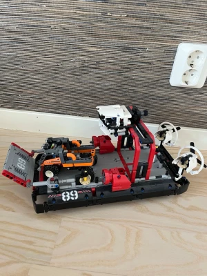 Lego Technic svävare med propellrar - Byggsats av Lego Technic som föreställer en svävare i svart, rött, vitt och orange. Modellen har två stora propellrar bak, detaljerad cockpit och nummer 83 på sidorna. Perfekt för dig som gillar teknik och kreativa byggen.